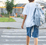 Schoolgirl in glasses with a beautiful smile goes to school. A girl crosses a pedestrian crossing. Student on the background of the school. High quality photo. Back view. - Городская Газета