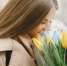 Beautiful girl in a brown coat. Woman in a spring city. Lady with bouquet of flowers - Городская Газета